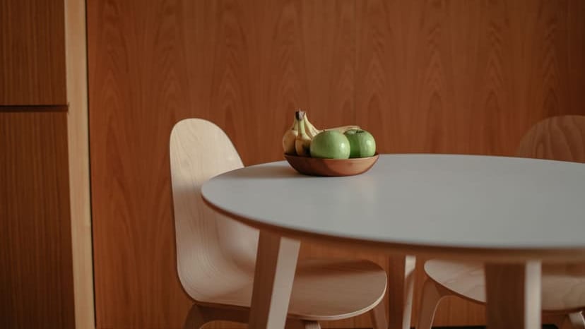 A simple fruit bowl with green apples and bananas on a sleek wooden table, perfect for a modern kitchen.
