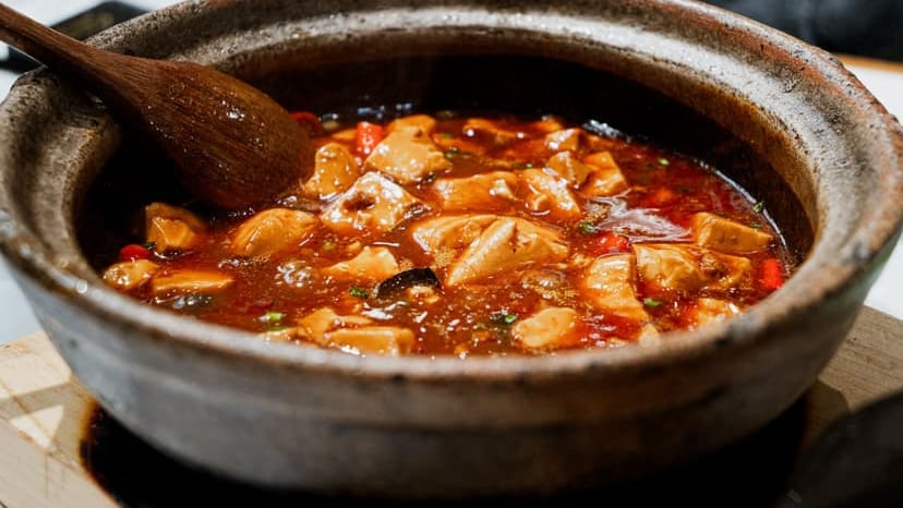 Close-up of a flavorful tofu stew simmering in a rustic pot with a wooden spoon.