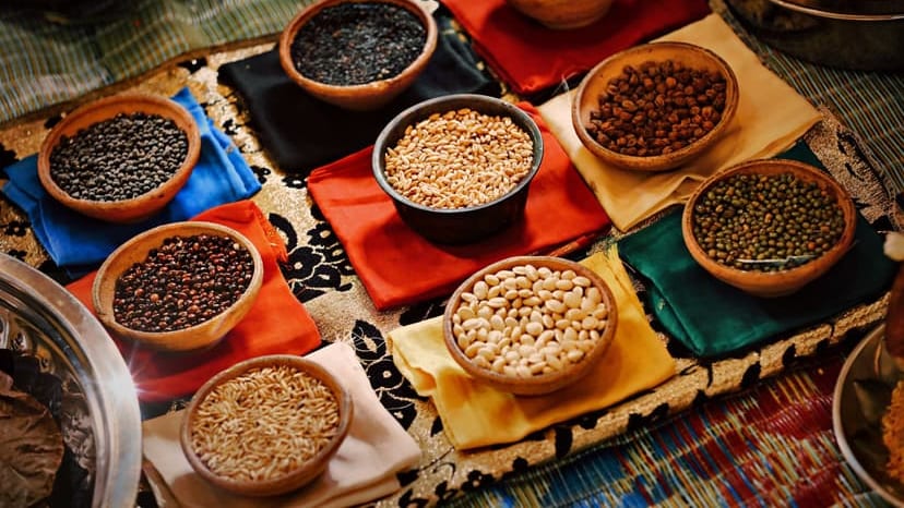 A vibrant assortment of grains and beans in ceramic bowls arranged on colorful textiles, showcasing diverse ingredients.