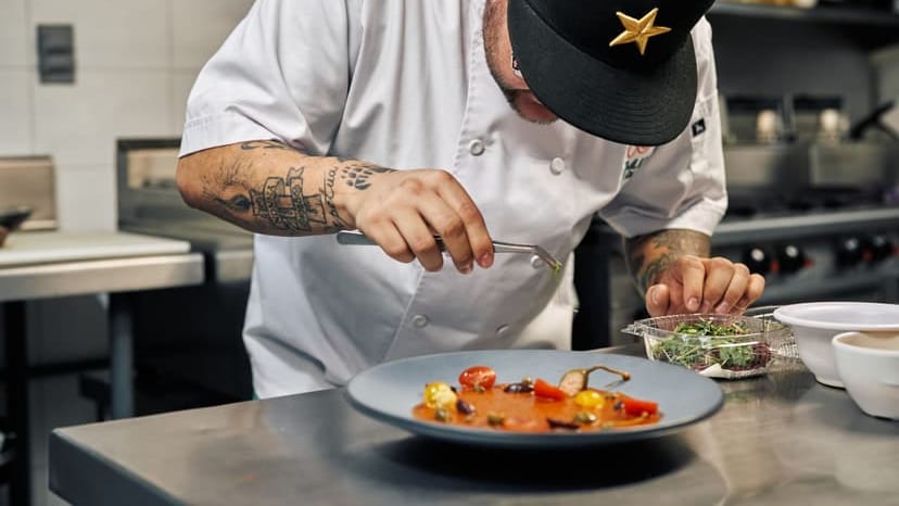 Close-up of a chef in a professional kitchen garnishing a gourmet dish with precision.